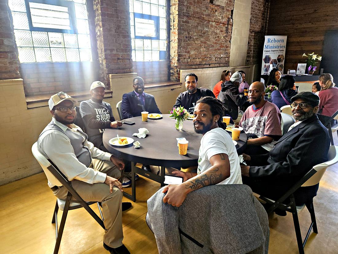 A room of people sitting and talking around tables at church
