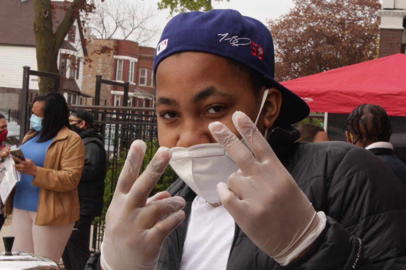 A young volunteer in gloves and a mask at a neighborhood giveaway