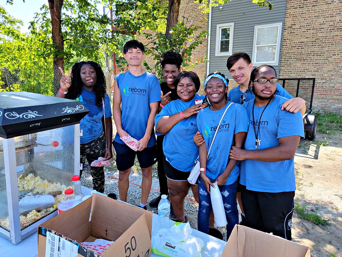 A group of young volunteers outside on a summer day at a neighborhood giveaway